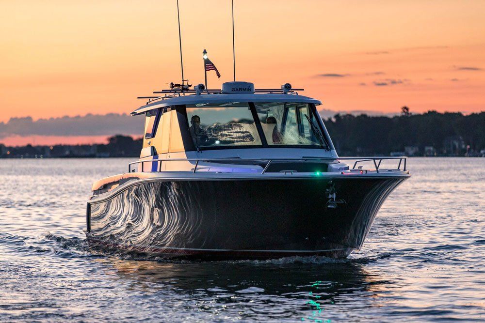 Boat cruising on water during sunset, with people visible inside.
