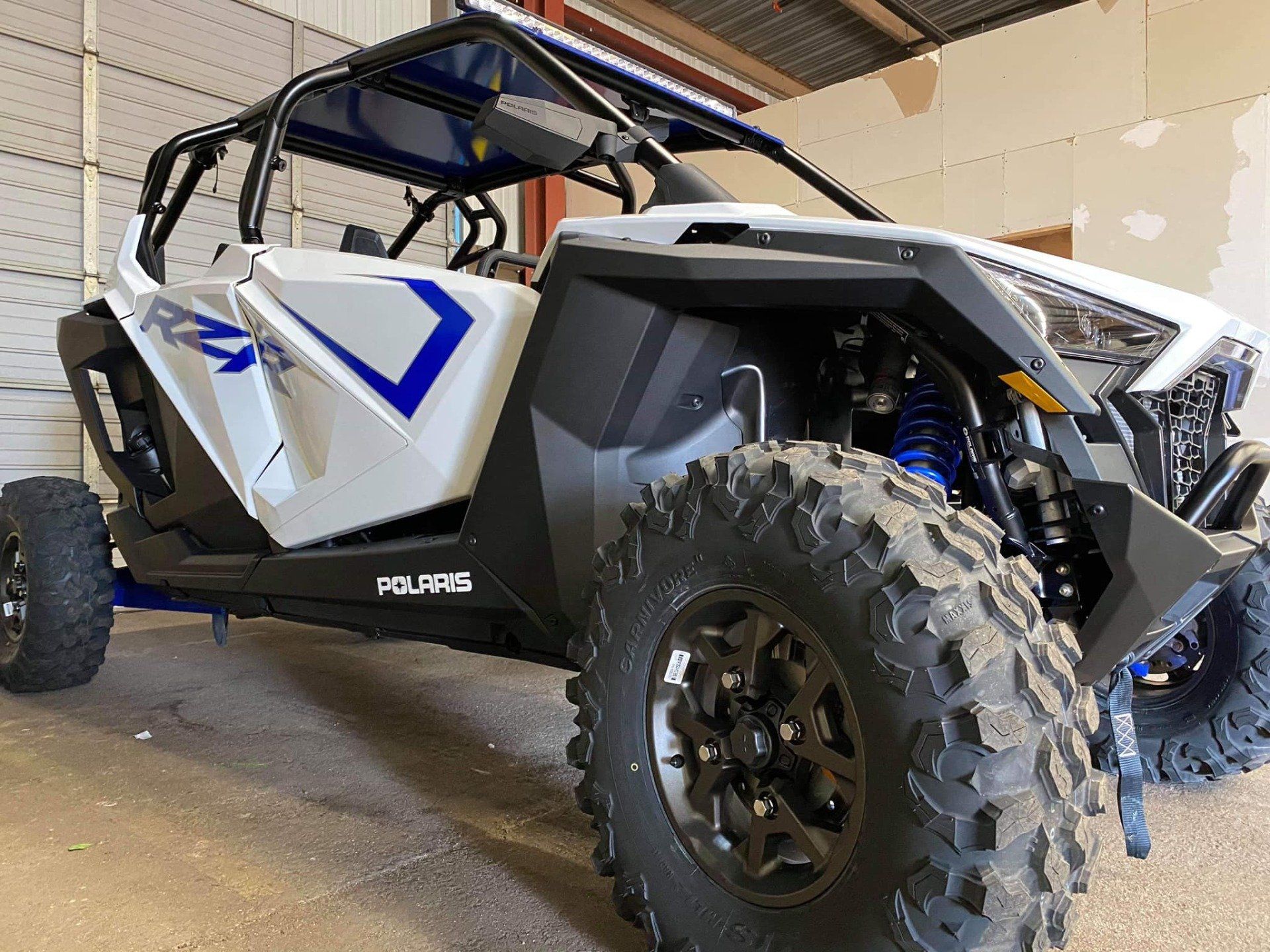 White and blue Polaris RZR side-by-side off-road vehicle with large tires.