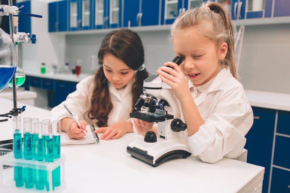 Two Young Girls In Lab Coats Learning Chemistry — Academic & Music Tutors in Newcastle NSW