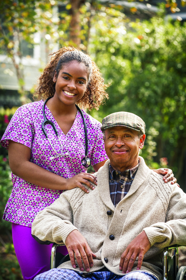 Home Health Care Nurse and Elderly Man in Wheelchair Smiling