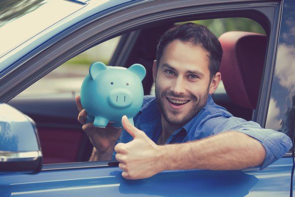 Happy Man Sitting Inside His New Car Holding Piggy Bank — Chicago, IL — Illinois Insurance Center Inc