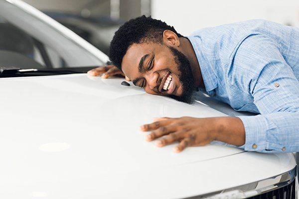 Happy Man Touching Hugging His Brand-New Car — Chicago, IL — Illinois Insurance Center Inc
