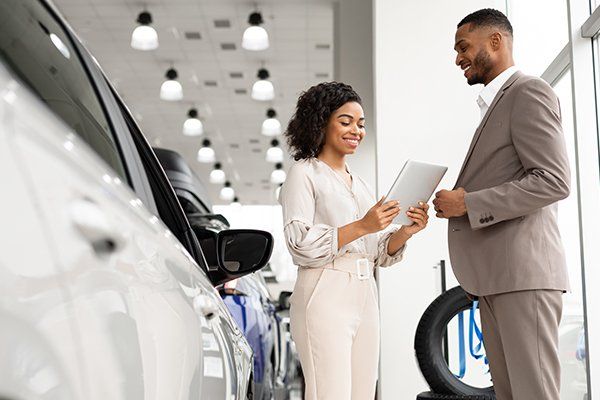 Seller Woman Showing Auto To Man In Dealership Showroom — Chicago, IL — Illinois Insurance Center Inc