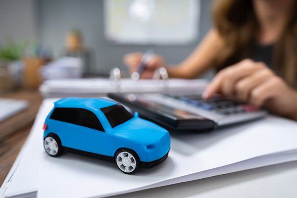 Blue Car in Front of Businesswoman Calculating Loan — Chicago, IL — Illinois Insurance Center Inc