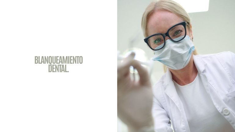 Anuncio de blanqueamiento dental con un dentista enmascarado con bata blanca sosteniendo un instrumento dental.