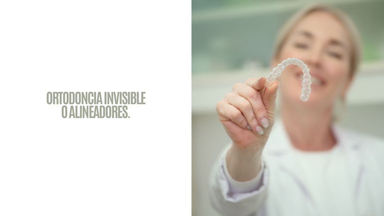 Alineador transparente sostenido por un ortodoncista sonriente en una clínica luminosa