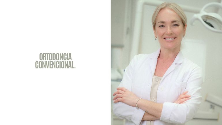 Banner de una clínica de ortodoncia con un dentista sonriente con bata blanca de pie con los brazos cruzados.