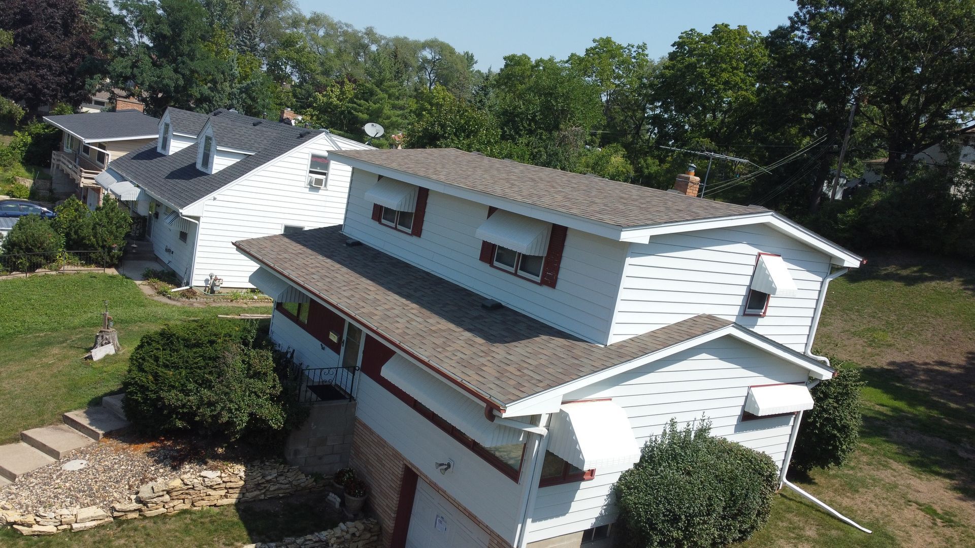 An aerial view of a white house with a brown roof