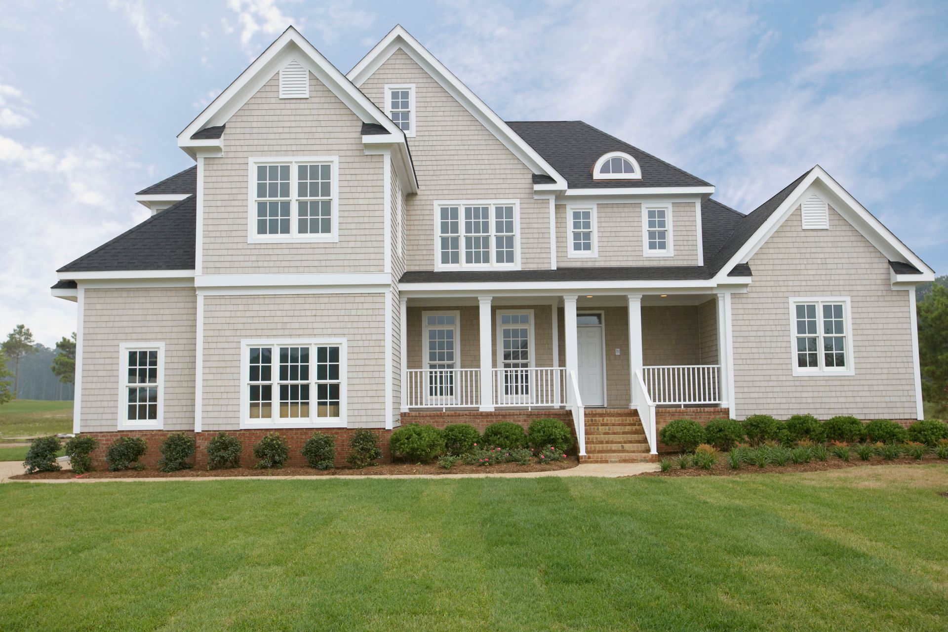 A black house with a lot of windows is surrounded by trees and leaves.