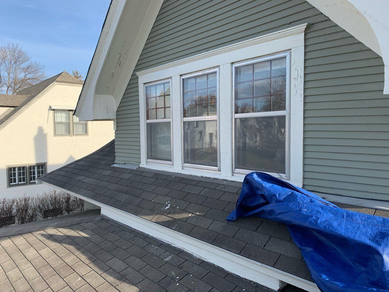 A blue tarp is sitting on the roof of a house.