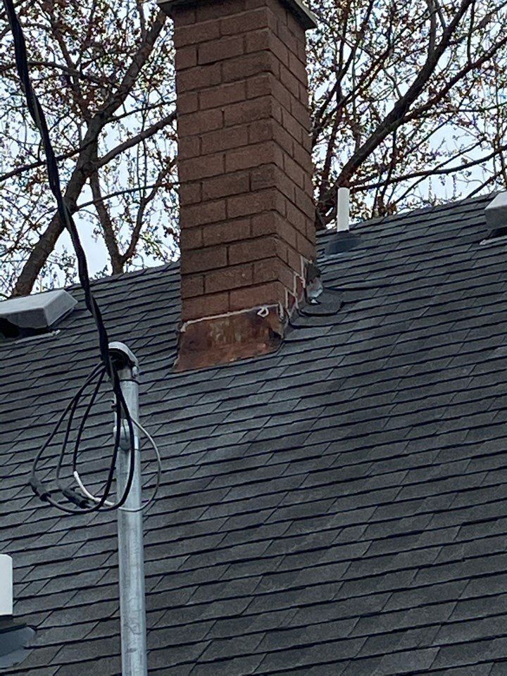 A brick chimney is on the roof of a house.