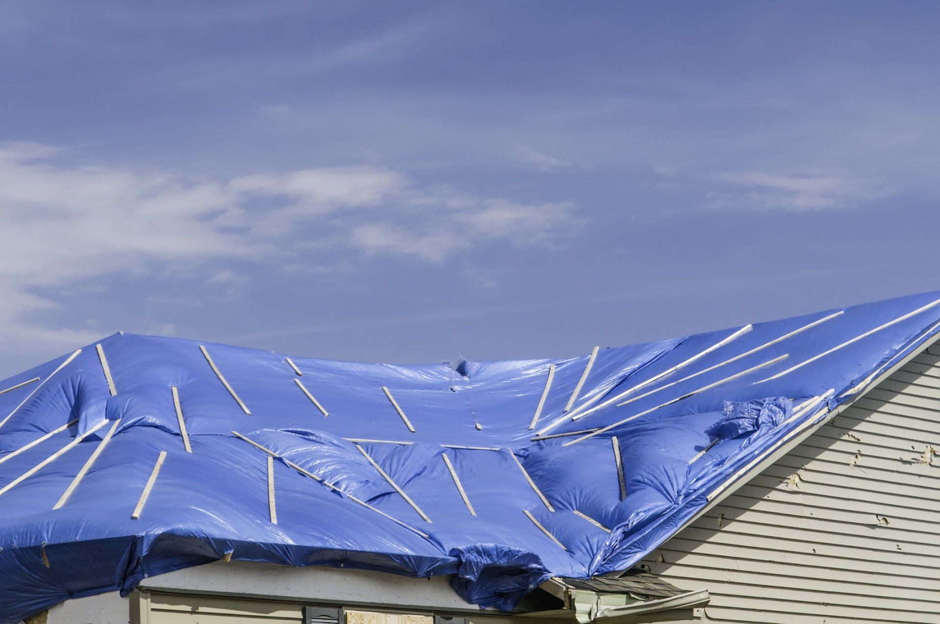 A blue tarp is covering the roof of a house.