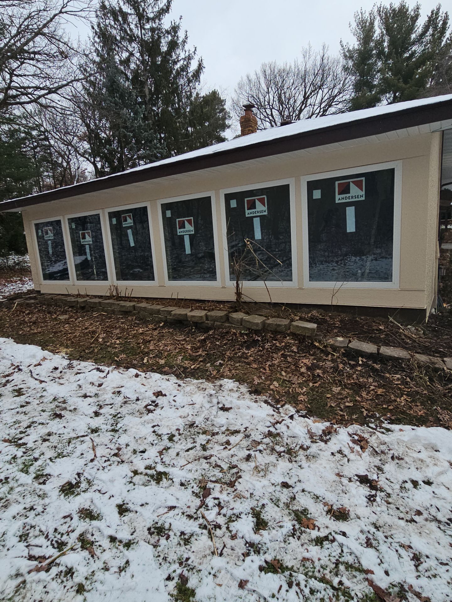 A house with a lot of windows is sitting in the snow.