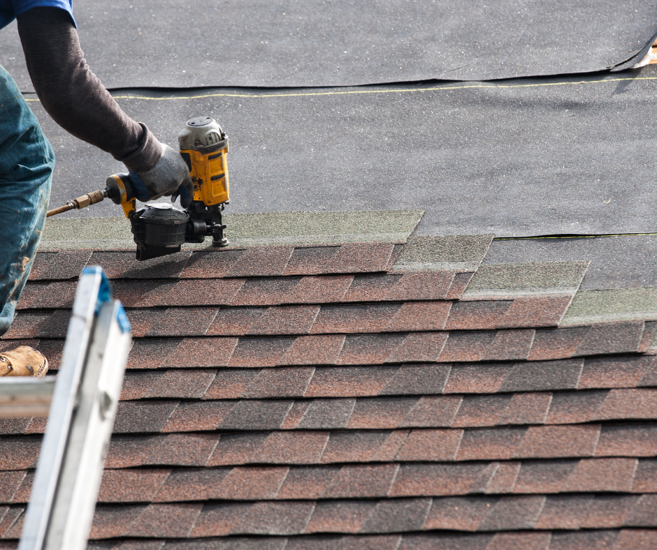 A Twin Cities roofer stapling brown shingles to the roof of a house