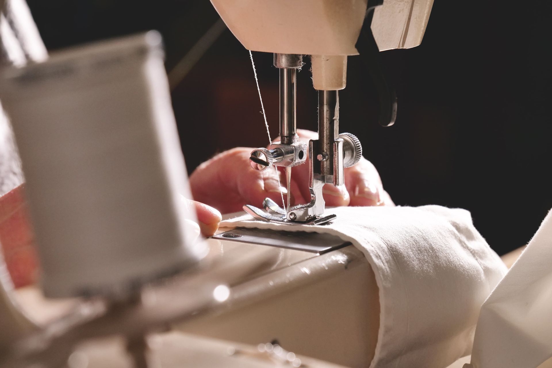 Hands sewing white fabric on a sewing machine close-up