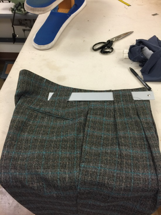 Plaid skirt panel laid on a worktable with scissors and blue fabric nearby