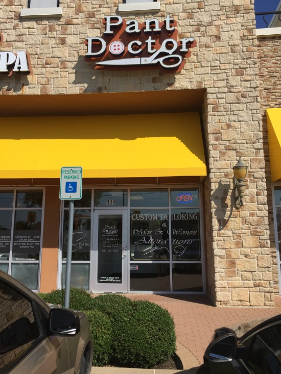 Pant Doctor storefront with yellow awning and stone facade in a shopping center