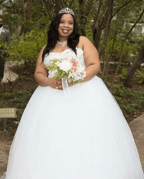 Bride in a white gown and tiara holding a bouquet in a garden setting