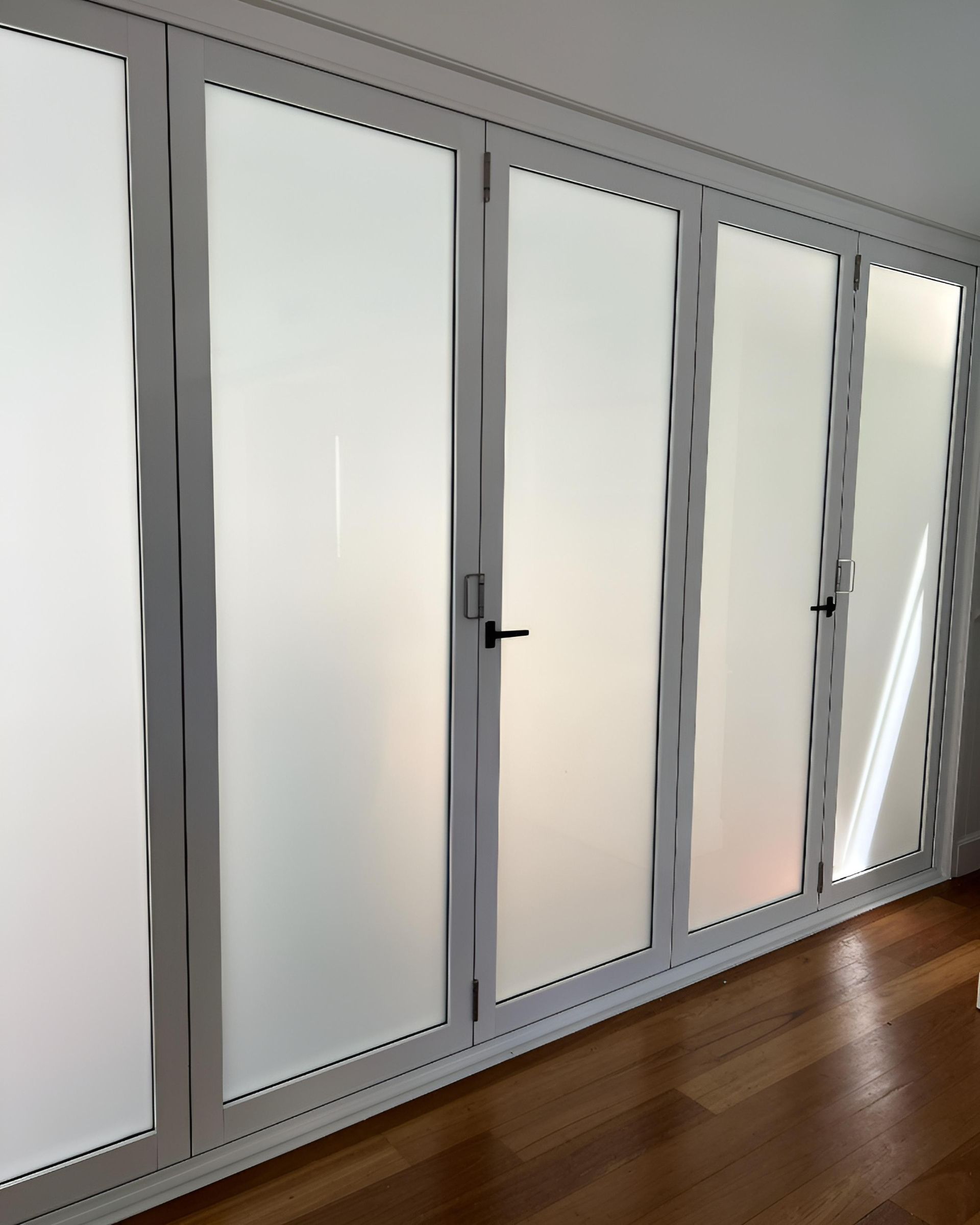 White-framed Frosted Glass Doors in a Row With a Black Door Handle — Architectural Glass Solutions QLD in Cooroy, QLD