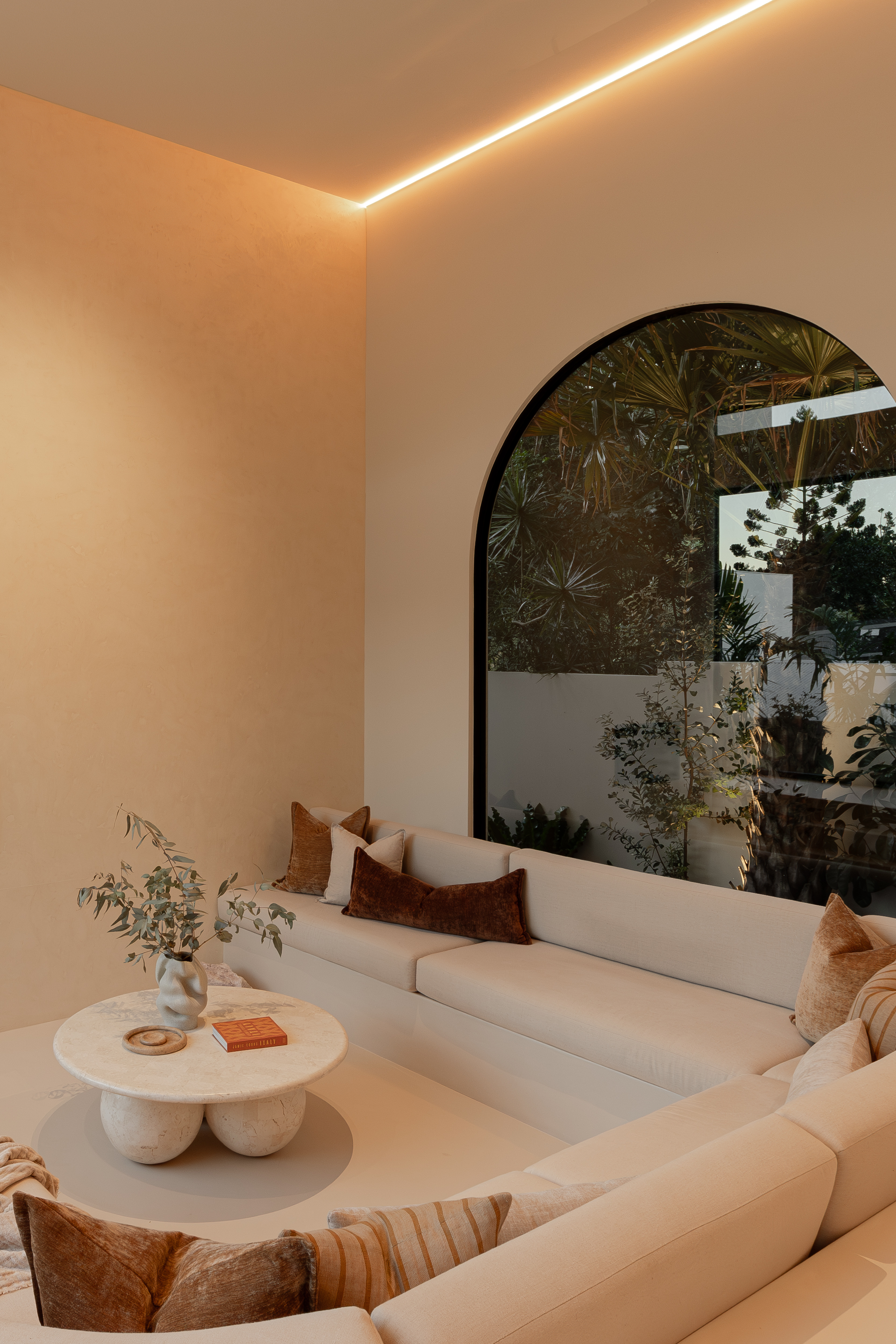 A Modern Living Space With Arched Window, Built-in White Seating and Table — Architectural Glass Solutions QLD in Cooroy, QLD