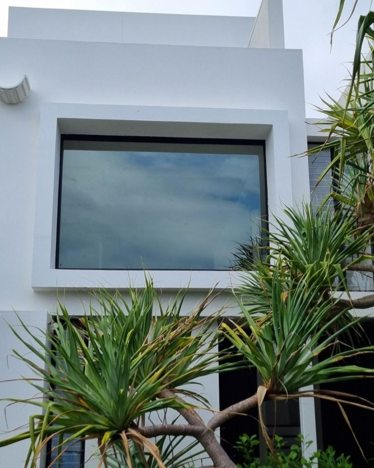 A White House with A Large Window and Palm Trees in Front of It — Architectural Glass Solutions QLD in Cooroy, QLD