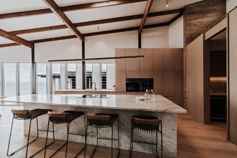 A Kitchen With a Large Island and Stools in It — Architectural Glass Solutions QLD in Cooroy, QLD