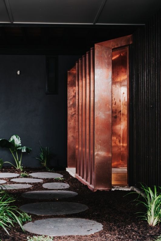 A Black Building With a Copper Door and a Stone Walkway Leading to It — Architectural Glass Solutions QLD in Cooroy, QLD