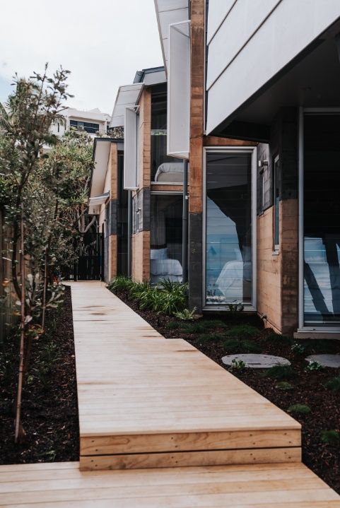 A Wooden Walkway Leading to a House With a Lot of Windows — Architectural Glass Solutions QLD in Cooroy, QLD