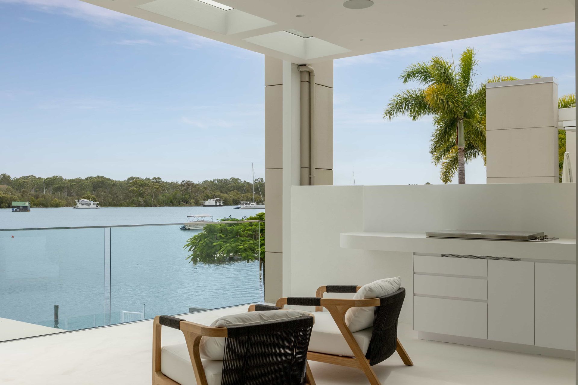 A patio with chairs and a table overlooking a body of water. — Architectural Glass Solutions QLD in Cooroy, QLD