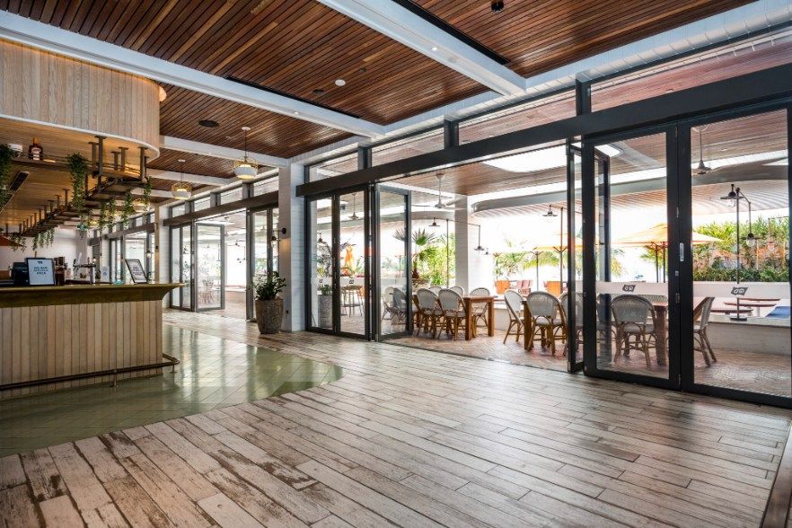 Bright Interior With Open Glass Doors, a Wooden Bar, and Tables/chairs — Architectural Glass Solutions QLD in Cooroy, QLD