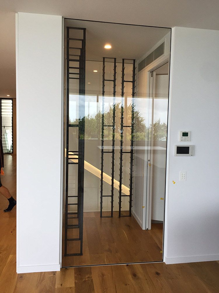 Glass Door With a Wine Rack, Set in a White Wall Interior — Architectural Glass Solutions QLD in Cooroy, QLD