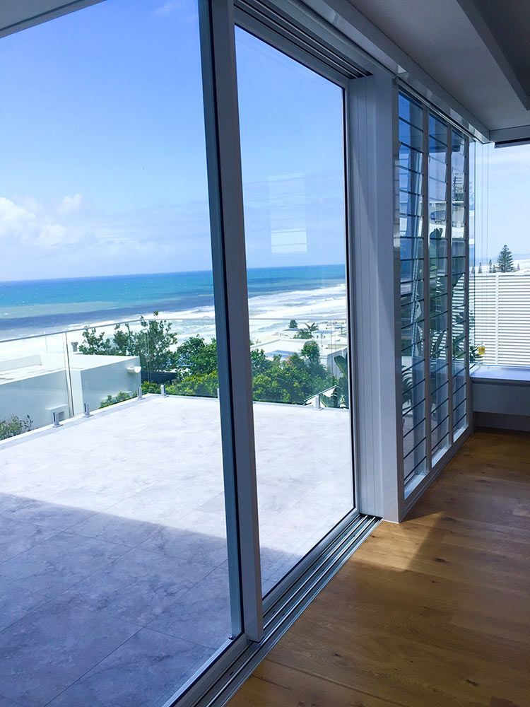Large Window With View of Beach Interior With Wood Floors & White Terrace — Architectural Glass Solutions QLD in Cooroy, QLD