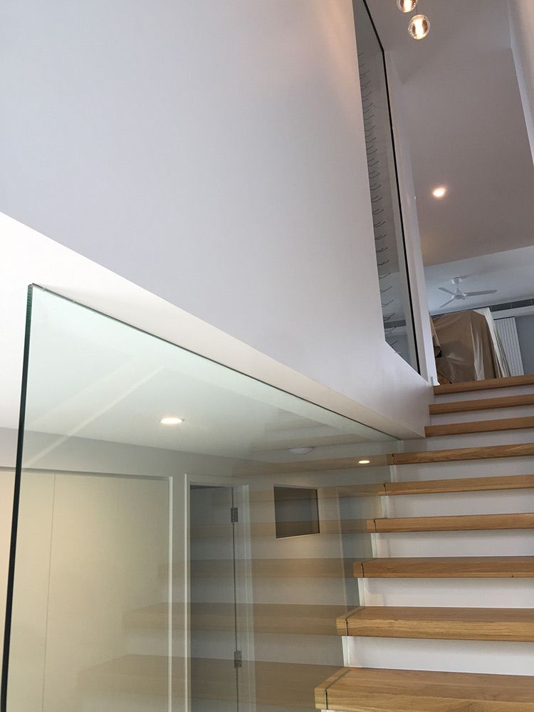 A Modern Staircase With Glass Railing and Wooden Steps — Architectural Glass Solutions QLD in Cooroy, QLD