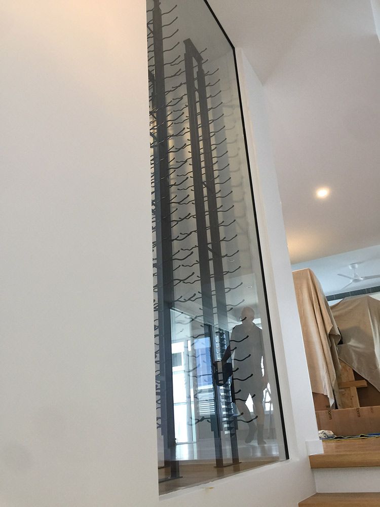 A Modern Wine Rack Built Into a Glass Wall, Displaying Many Wine Bottles — Architectural Glass Solutions QLD in Cooroy, QLD