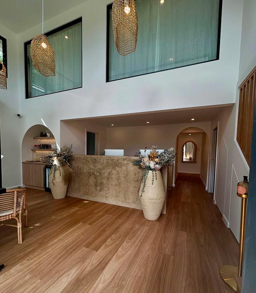 Reception Area With Stone Counter, Floral Arrangements & Wooden Floors — Architectural Glass Solutions QLD in Cooroy, QLD