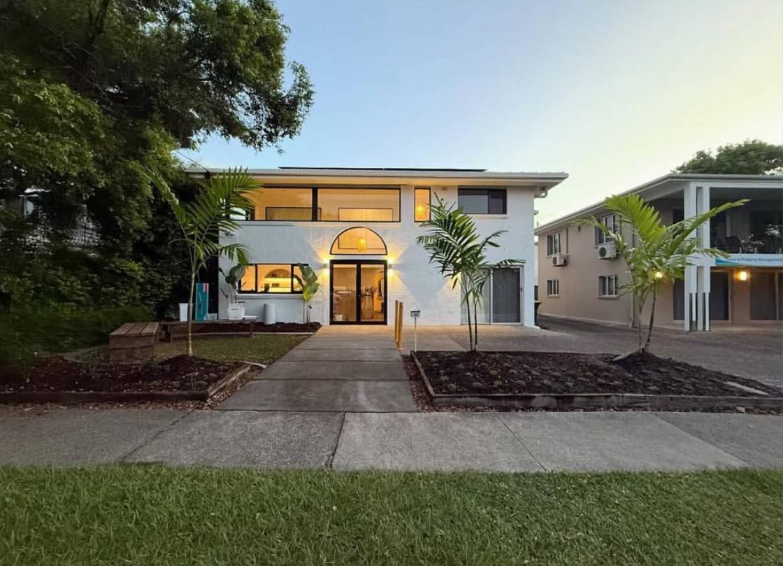 White Two-story Building With Arched Entryway and Palm Trees in Front — Architectural Glass Solutions QLD in Cooroy, QLD