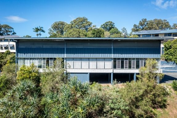 A Large House is Sitting on Top of a Hill Surrounded by Trees — Architectural Glass Solutions QLD in Cooroy, QLD