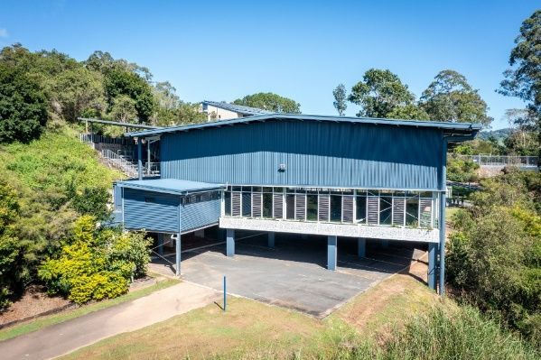 A Large Blue Building is Sitting on Top of a Hill Surrounded by Trees — Architectural Glass Solutions QLD in Cooroy, QLD