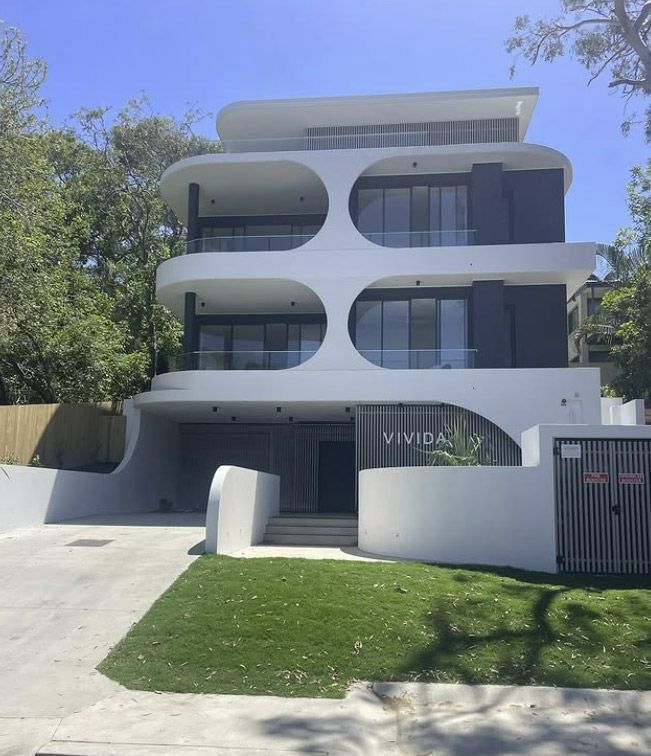 A White Apartment Building With Circular Cutouts Balconies, Dark Accents — Architectural Glass Solutions QLD in Cooroy, QLD