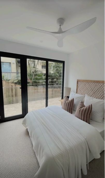 Bedroom With White Bedding, a Wicker Headboard, and a White Ceiling Fan — Architectural Glass Solutions QLD in Cooroy, QLD