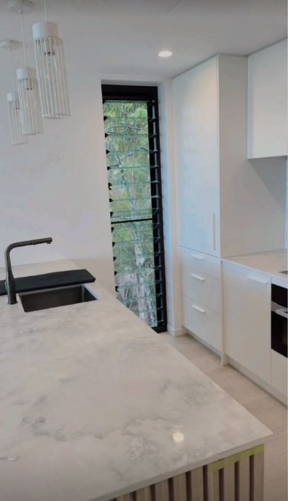 Kitchen With White Cabinets, Countertop and a Long, Vertical Window — Architectural Glass Solutions QLD in Cooroy, QLD