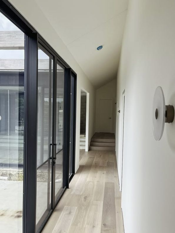 Hallway With Light Wood Floors, White Walls, and Black-framed Glass Doors — Architectural Glass Solutions QLD in Cooroy, QLD