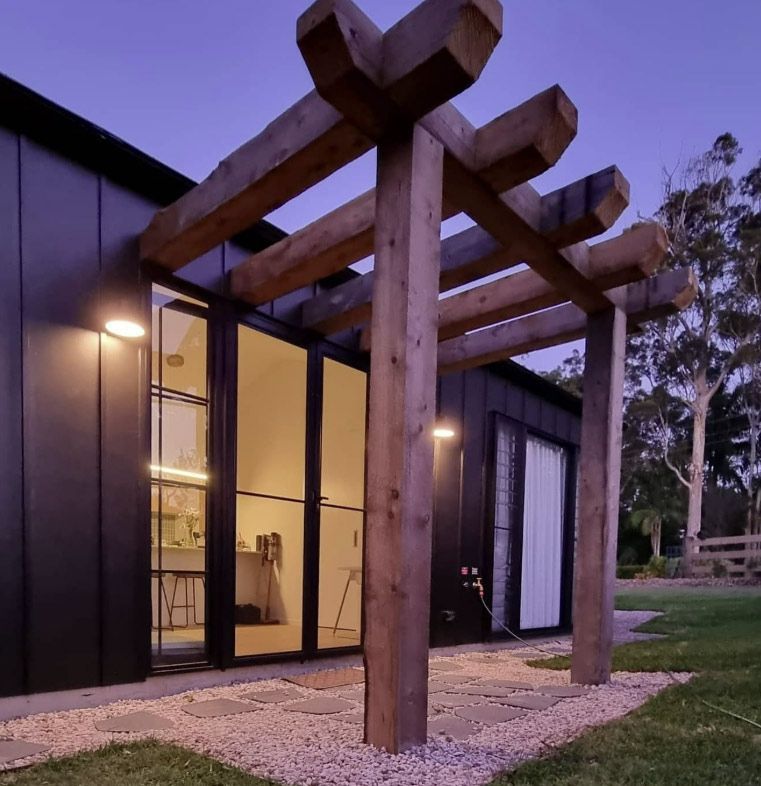A Dark Exterior of a Modern Home With a Wooden Pergola at Dusk — Architectural Glass Solutions QLD in Cooroy, QLD