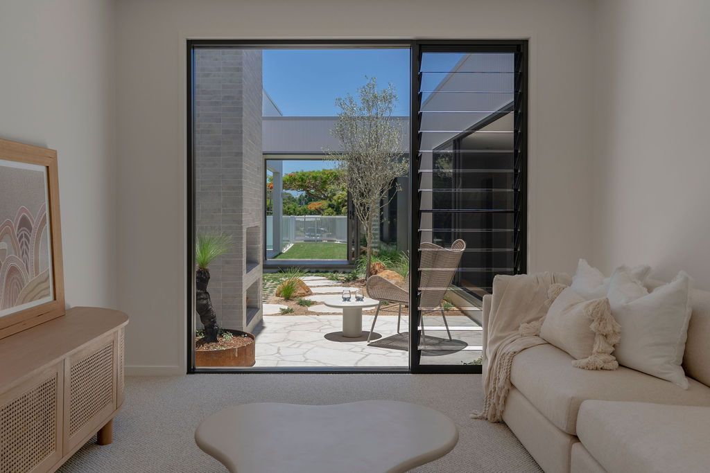 Beige living room with large window looking onto a sunny courtyard — Architectural Glass Solutions QLD in Cooroy, QLD