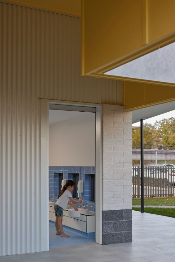 A Woman is Washing Her Hands in a Bathroom in a Building — Architectural Glass Solutions QLD in Cooroy, QLD