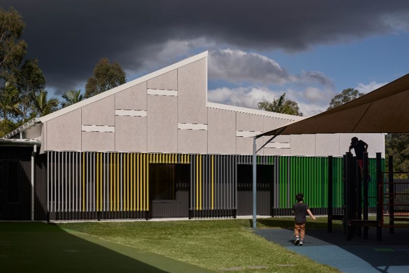 A Boy is Standing in Front of a Building With Playground — Architectural Glass Solutions QLD in Cooroy, QLD