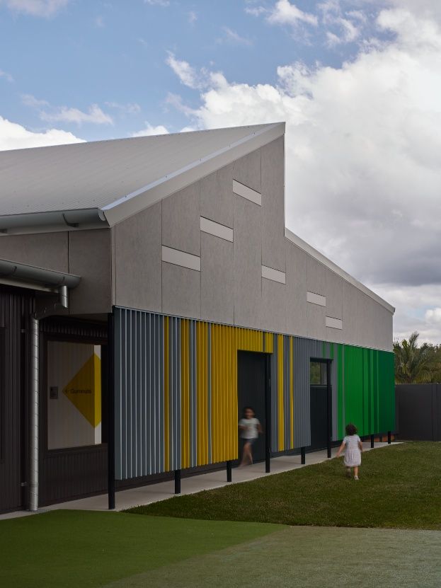 A Little Girl is Running in Front of a Building With Colorful Siding — Architectural Glass Solutions QLD in Cooroy, QLD