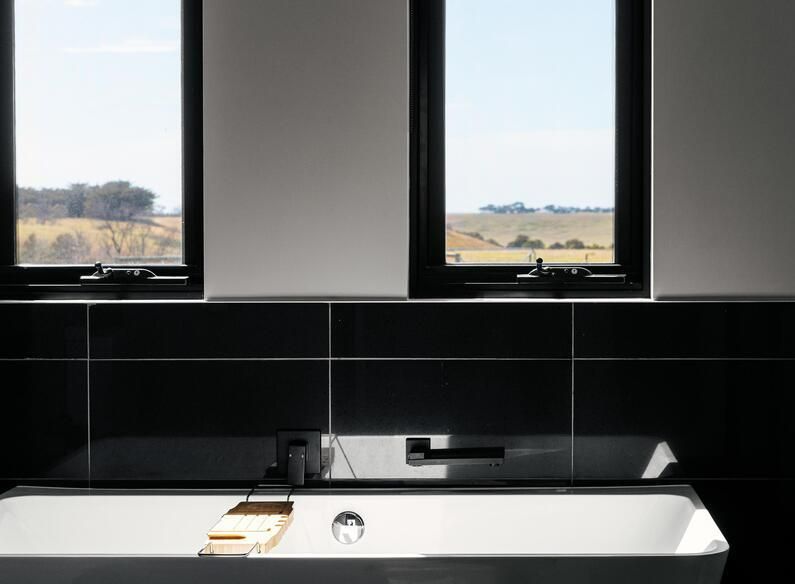 Bathroom With Black Tile, a White Bathtub, and Windows — Architectural Glass Solutions QLD in Cooroy, QLD