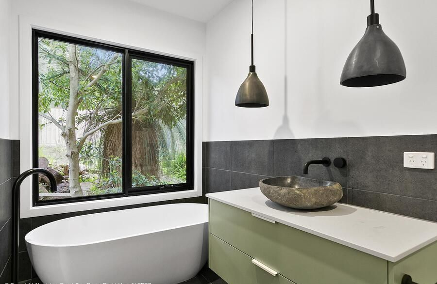 Bathroom With a Freestanding White Tub, a Green Vanity With a Stone Sink — Architectural Glass Solutions QLD in Cooroy, QLD