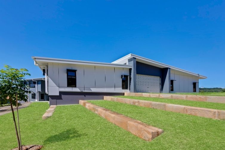 A Large White House is Sitting on Top of a Lush Green Hill — Architectural Glass Solutions QLD in Cooroy, QLD